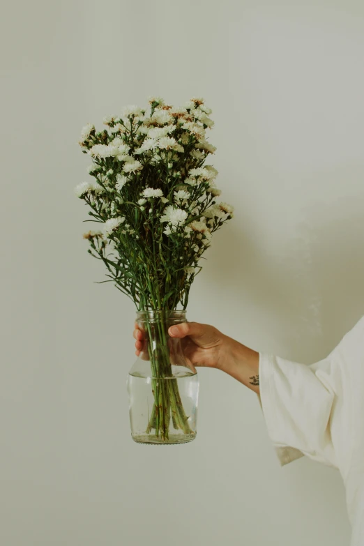 a hand holding a glass filled with water holding a bouquet of flowers