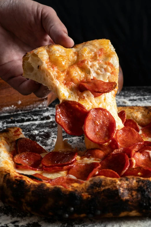 a person grabbing a slice of pepperoni pizza from a plate