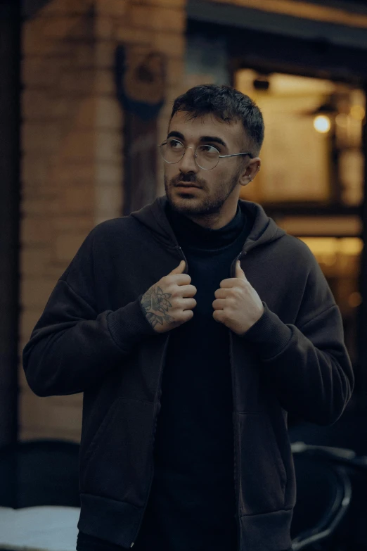 a man in black jacket and glasses in a room