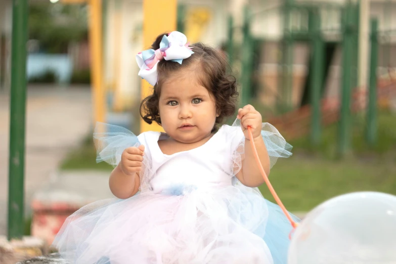 a little girl holding a wand and wearing a white and blue dress