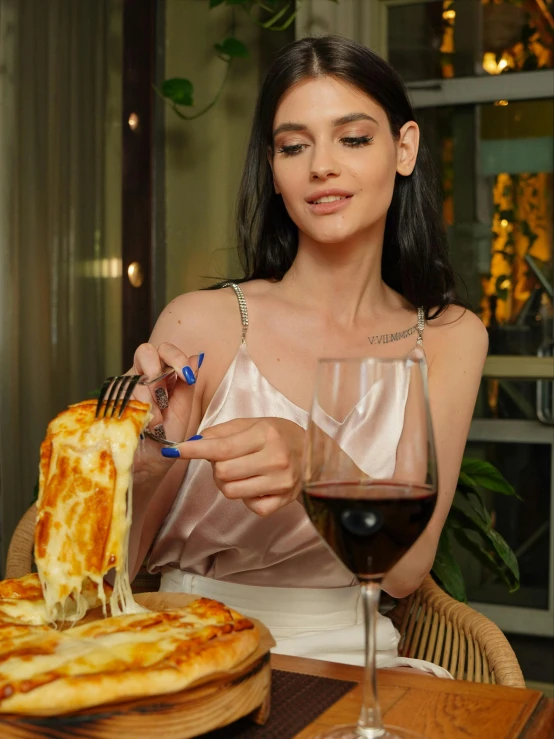 the woman is sitting at the table with a plate of food and wine