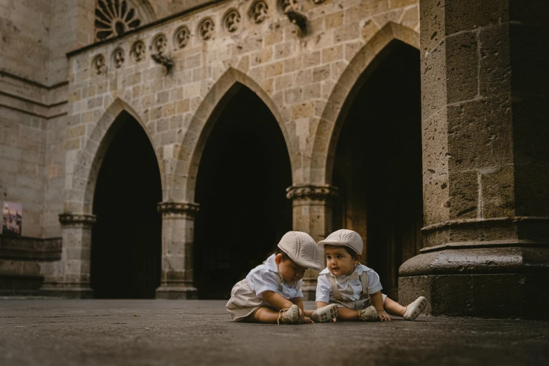 two small children sit on the ground with hats