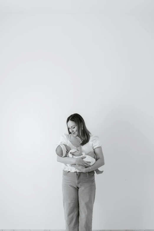 a woman standing next to a wall and holding her baby