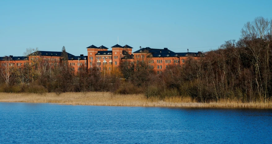 a very old brick building by the side of a lake