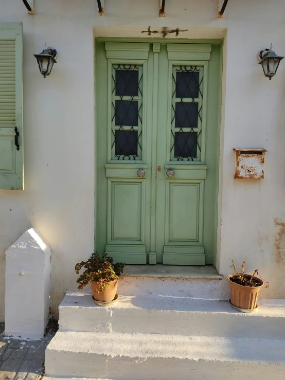 two pots and flowers are sitting outside of the door