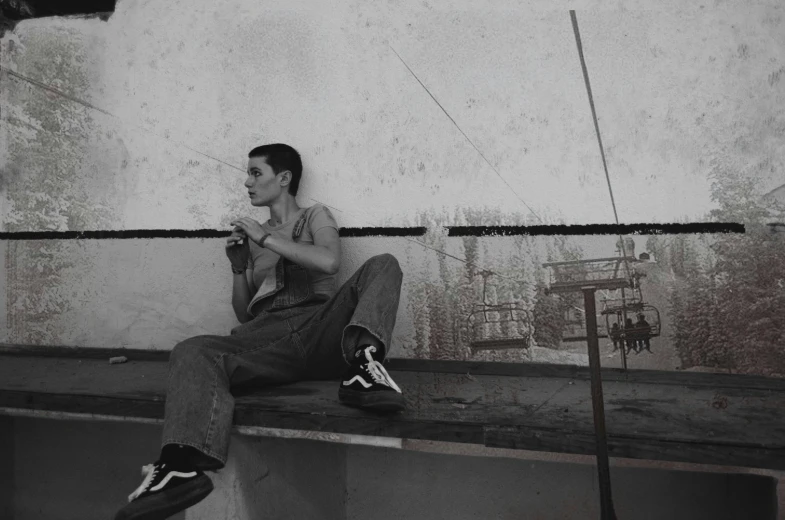 a young man sitting on a wall with a basketball and his skateboard