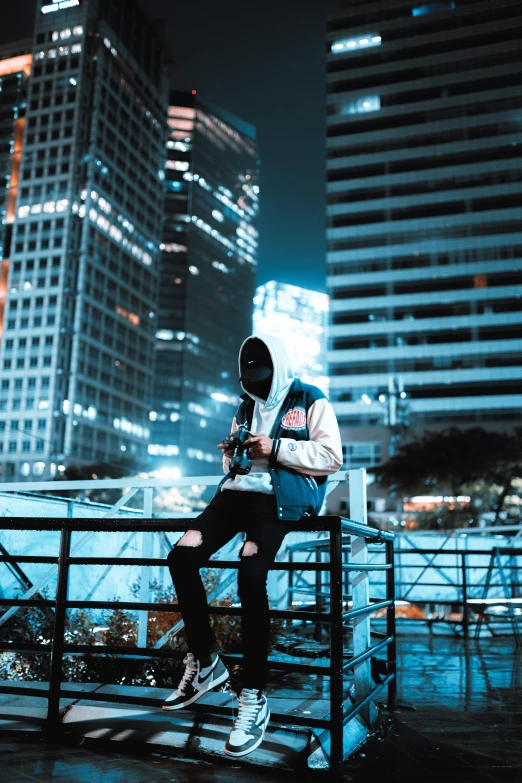 a man in a hoodie sitting on top of a bench