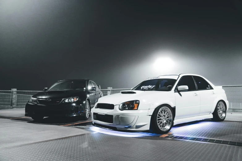 two car are parked in front of a fence