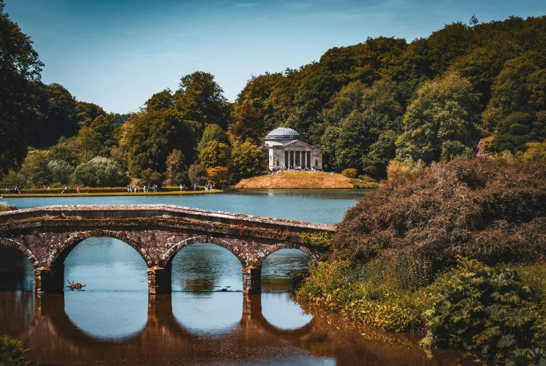 the bridge is across the river on it's way to a pavilion