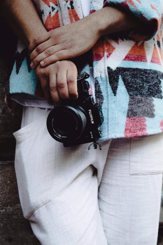 a woman wearing white trousers holding onto a camera