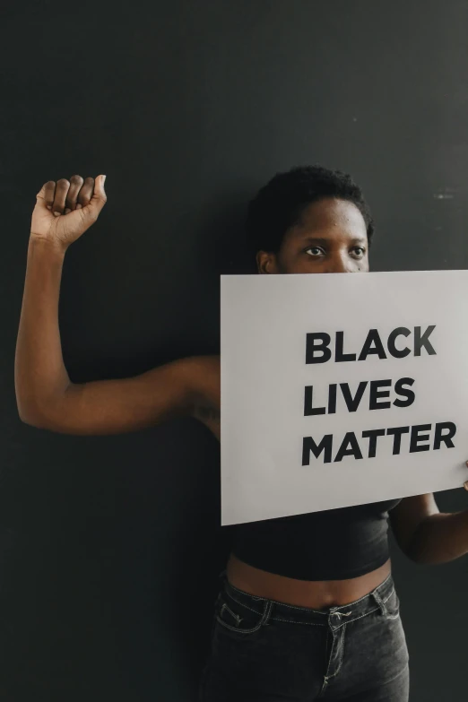 a young woman holds up a sign that reads black lives matter