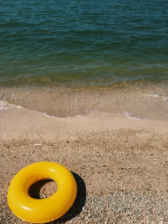 the yellow ring is lying on the sand of the beach