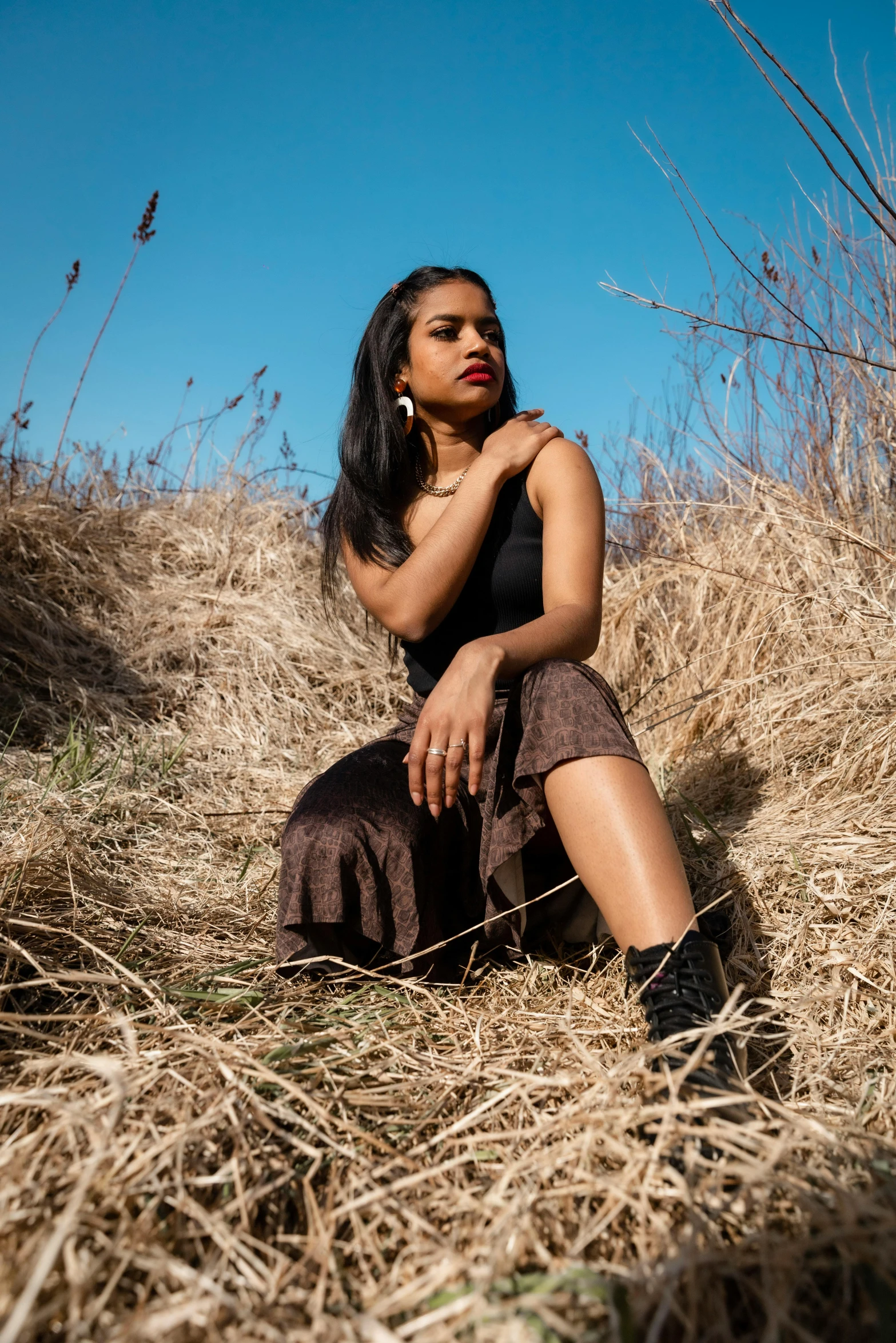 a woman in dress sitting on dry grass