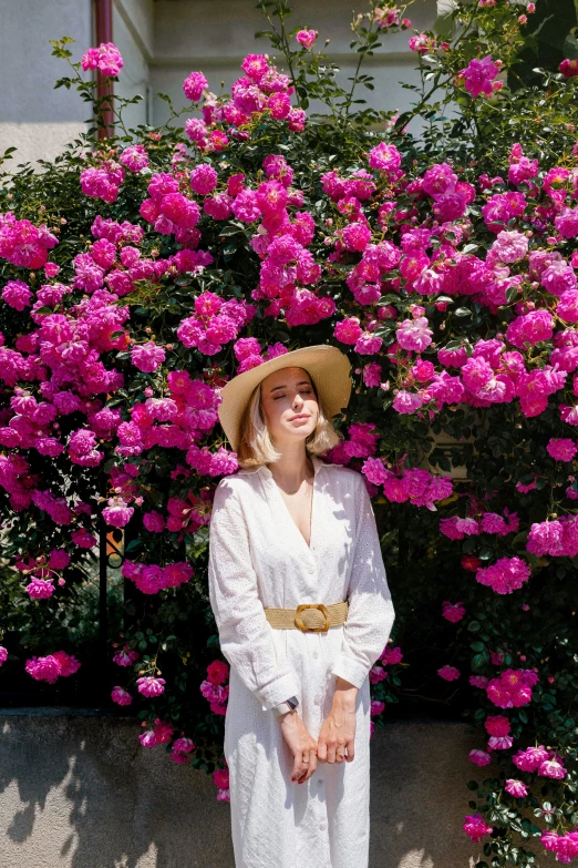 a woman standing in front of pink flowers