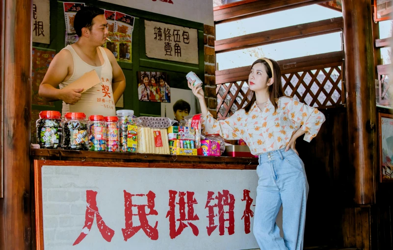 a woman in blue jeans is standing behind a counter with food