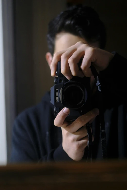 a young man holding up a camera with one hand