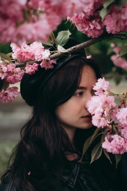 the woman is standing under the blossomy tree