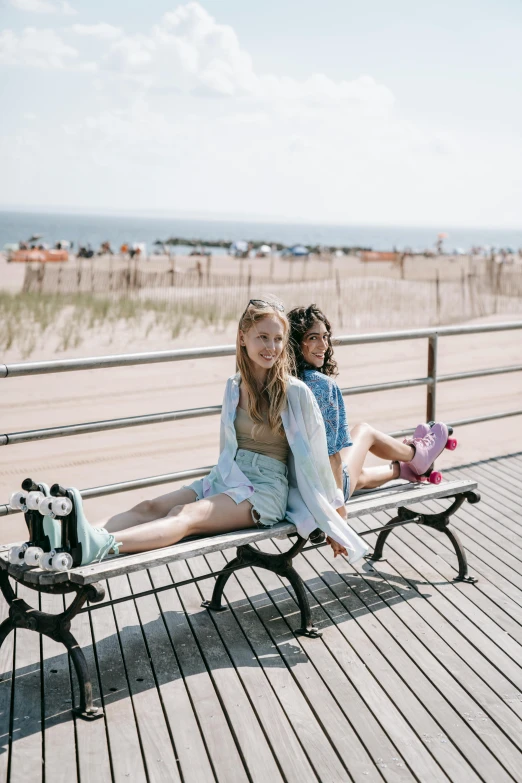 two girls sitting on a bench on the beach