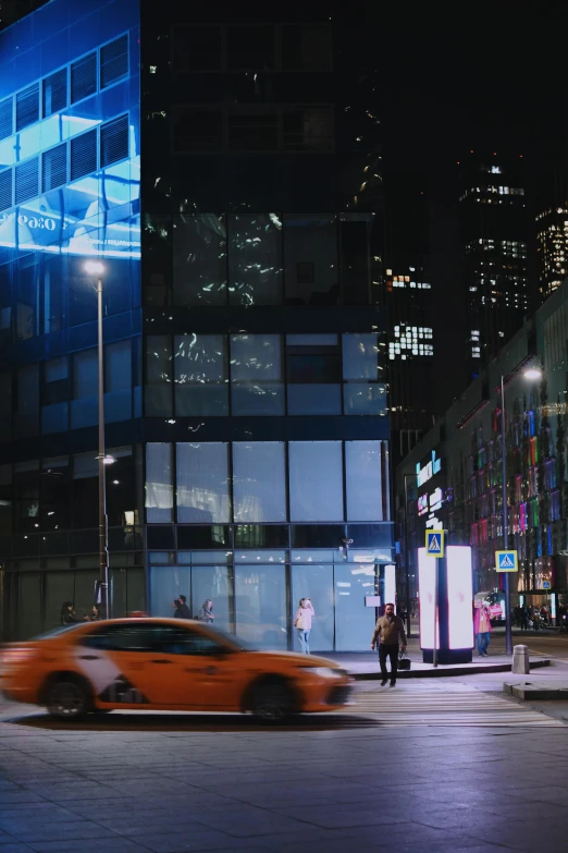 a car driving past tall buildings at night