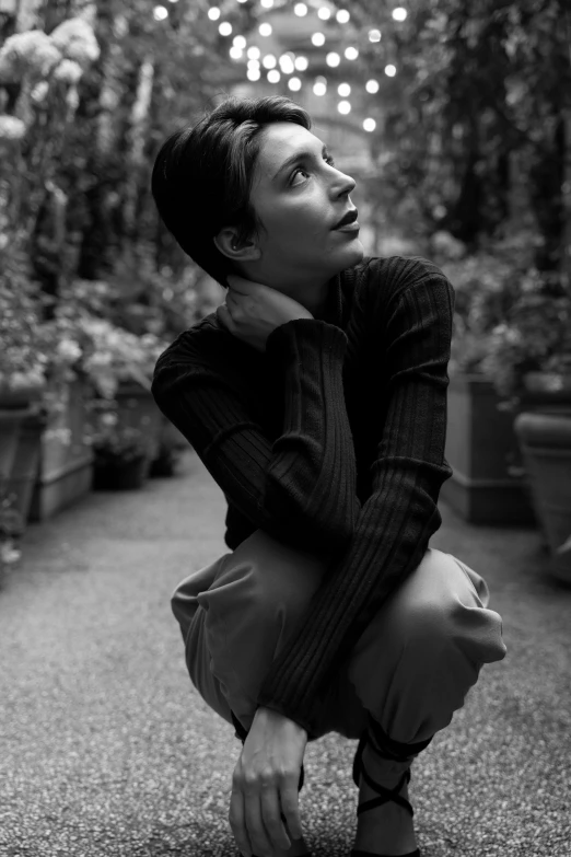 a woman is squatting in front of plants