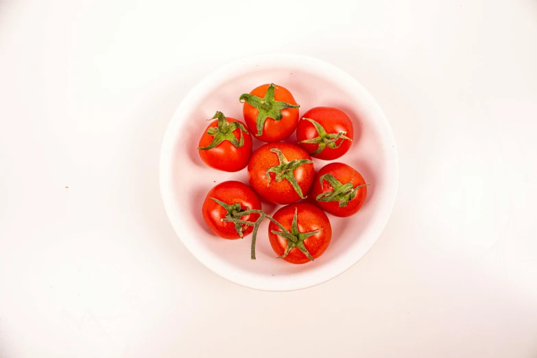 a white bowl filled with lots of ripe tomatoes