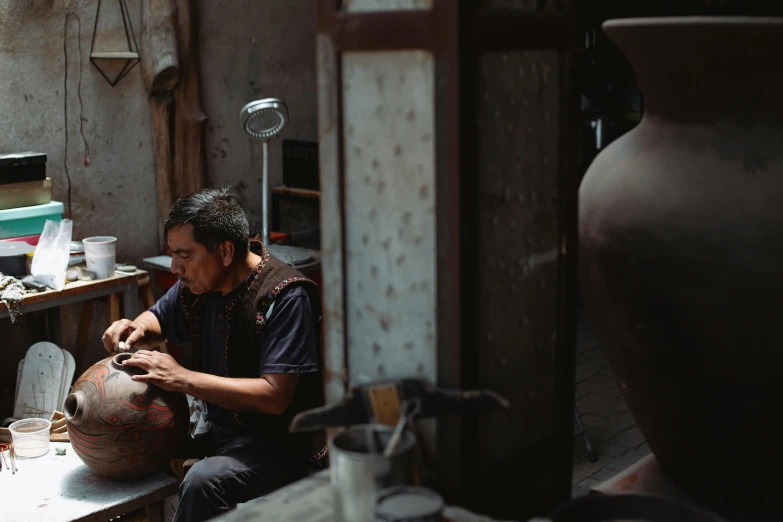 a man in black shirt using scissors to trim a vase