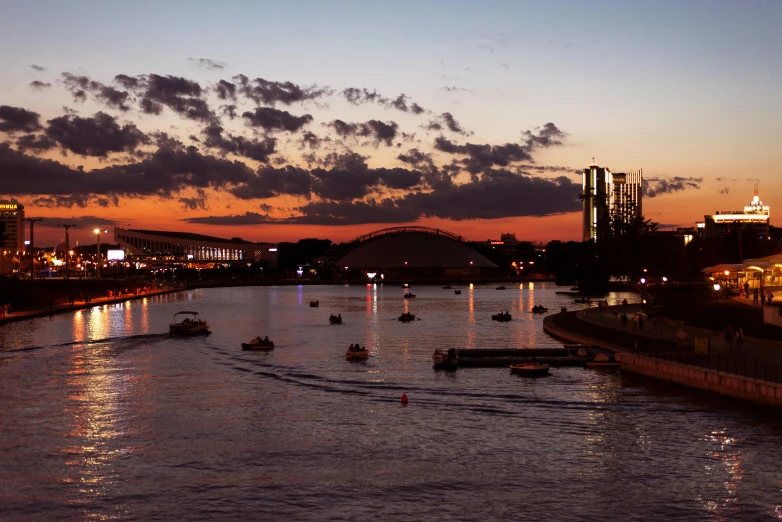 the skyline is reflected in the water as boats sail along