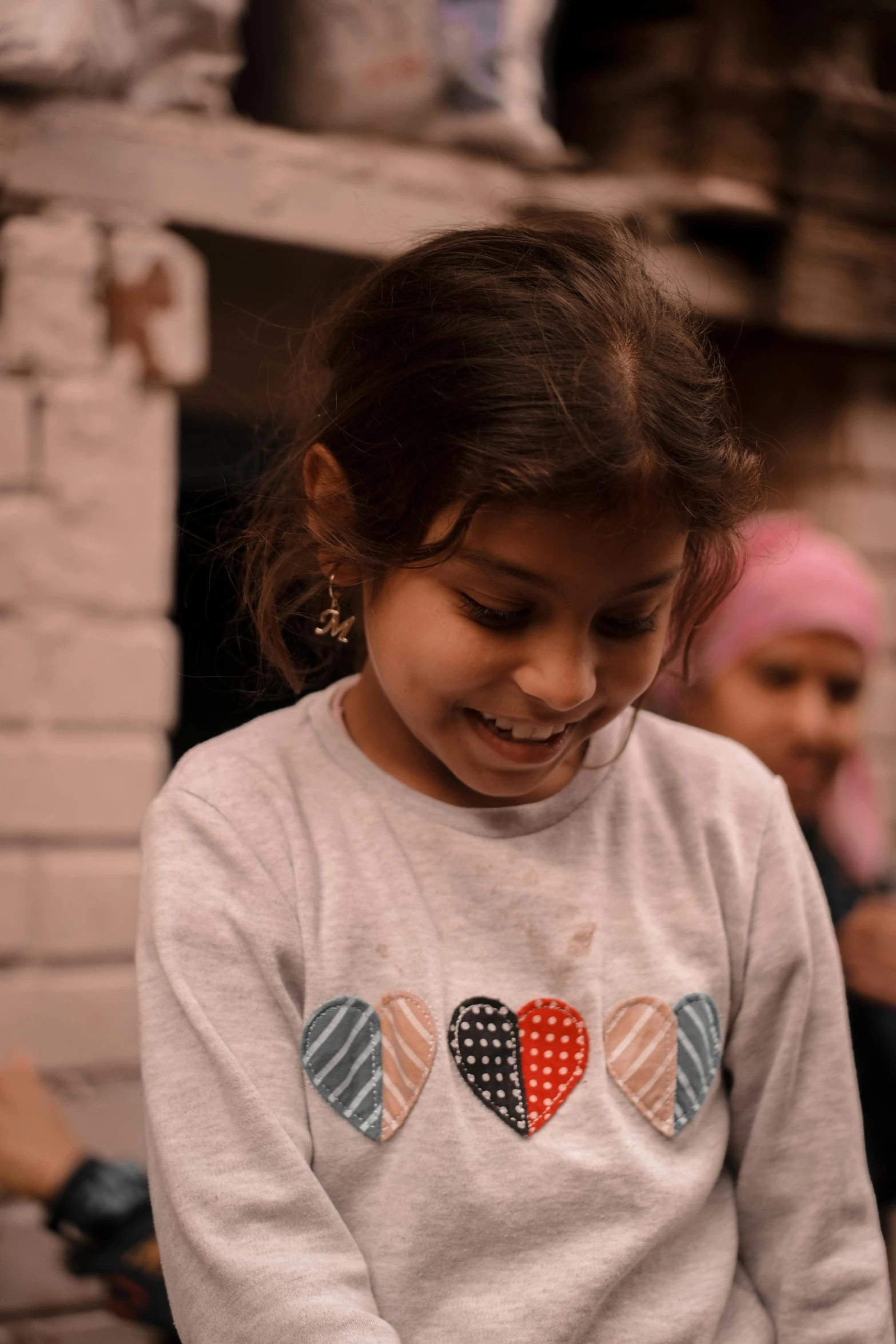 a little girl holding a donut with two hearts on it