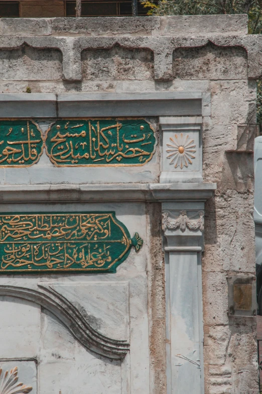 two green and gold plaques are attached to a stone wall