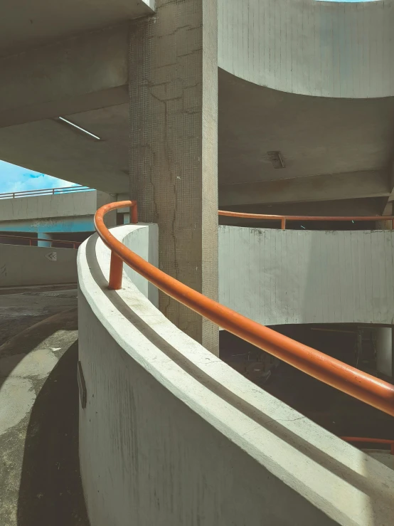 an orange handle on a white railing near concrete wall