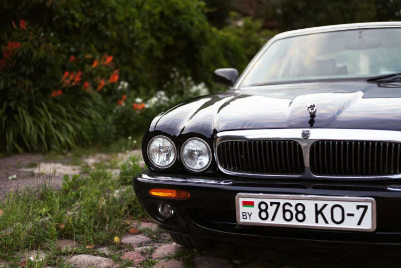 a black sporty car is parked by some flowers