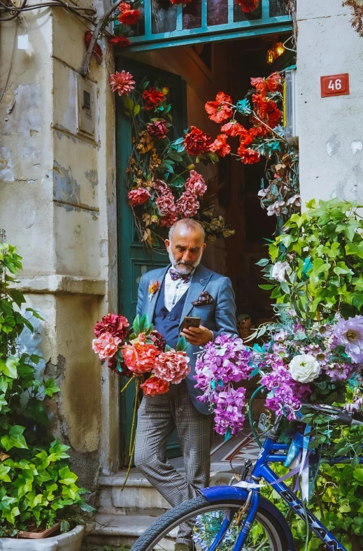 a man in a suit standing with flowers next to his bike