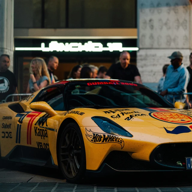 a sports car with a painted body is parked in front of a crowd