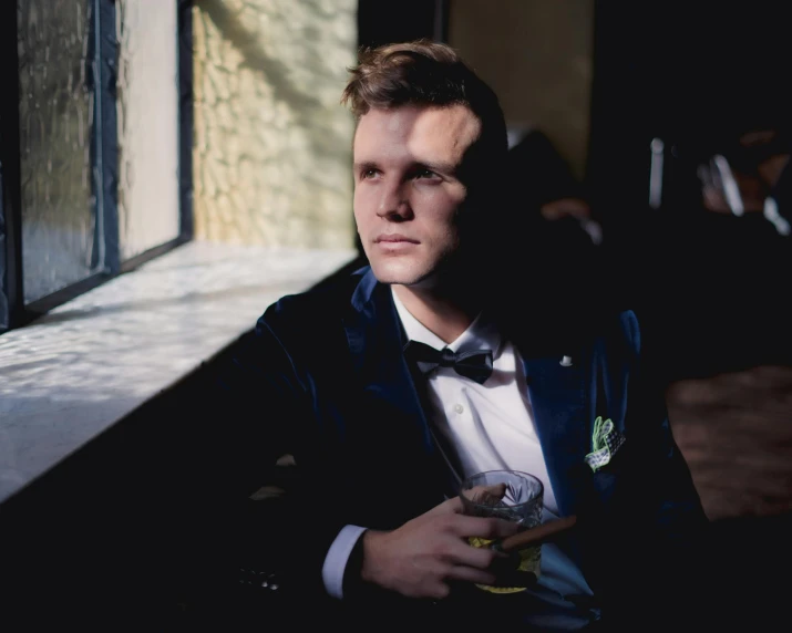 a man with a tuxedo looking out of a window