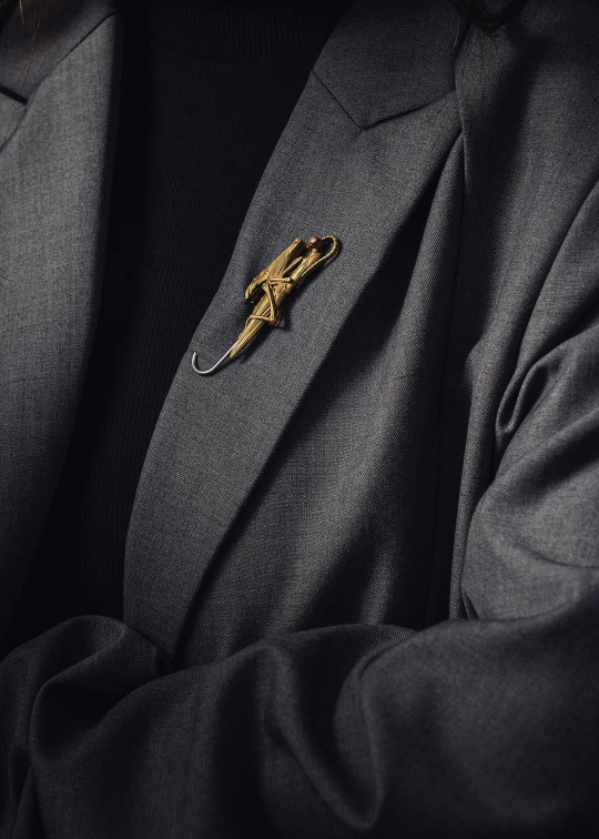 the front side of a black suit and gold lapel