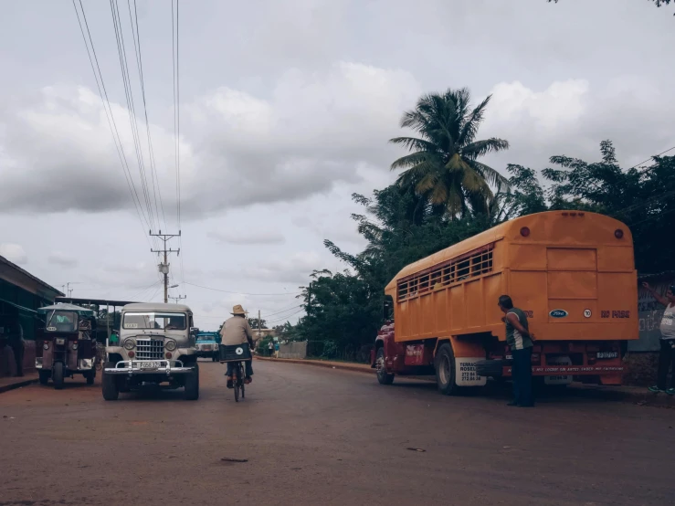 an old man riding a bicycle behind his truck on the side of the road