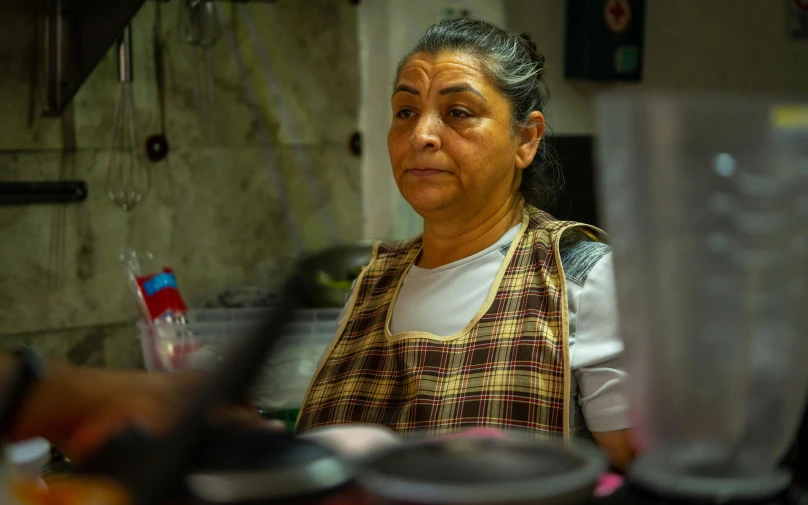 an old woman with gray hair stands in the kitchen