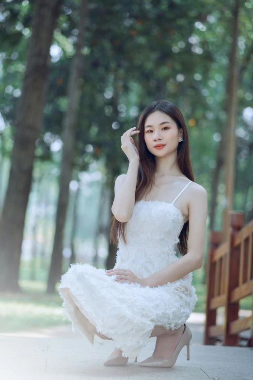 a young woman is kneeling down near some trees