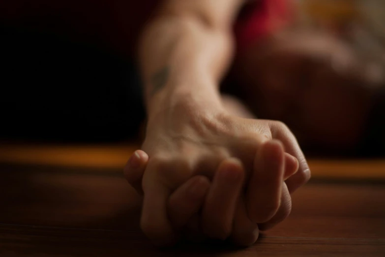a person holding their hand on a wooden surface