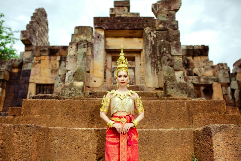 a woman in a costume standing in front of an ancient structure