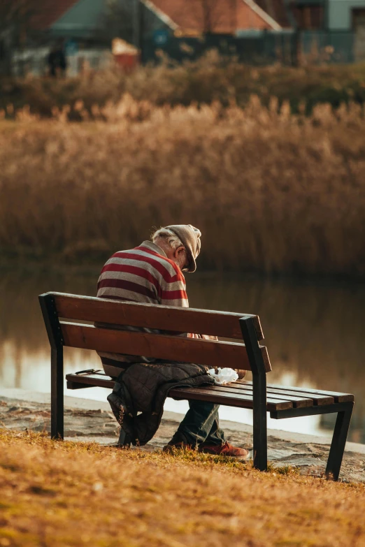 a man sits on a bench near the water