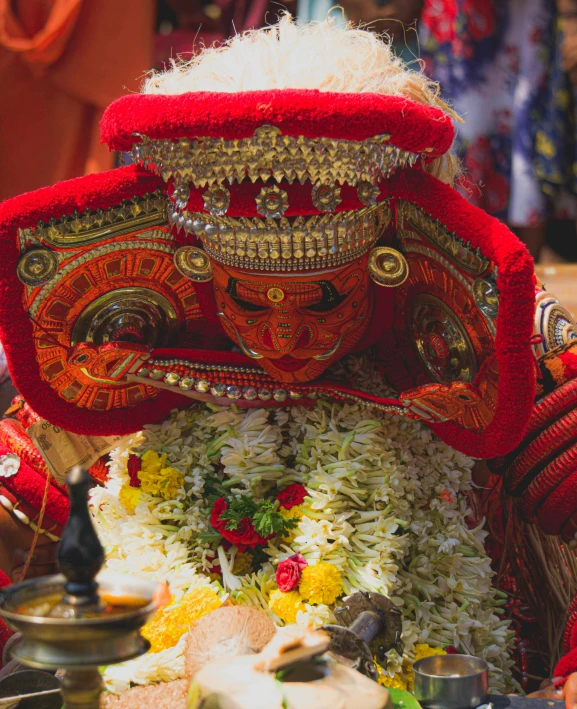 woman with headgear covered with red flowers near a statue