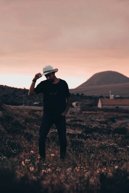 a man stands on a grassy hill, near mountains