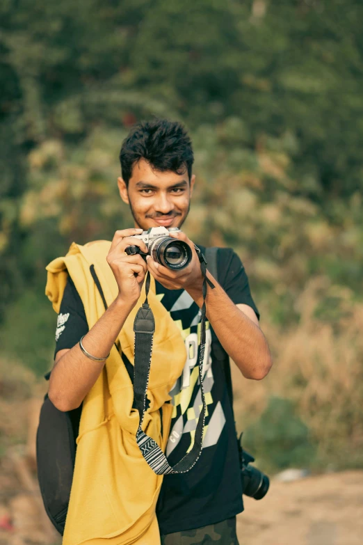 man holding up camera in his right hand with a blurry background