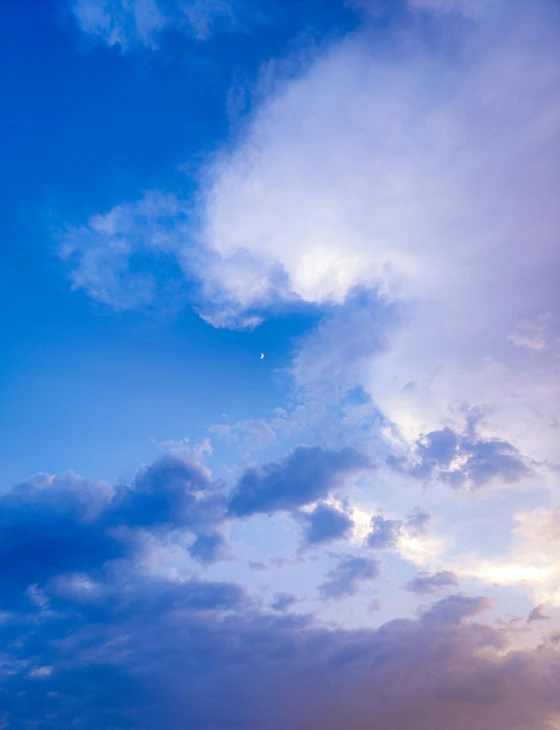 a large plane flying through a cloudy blue sky