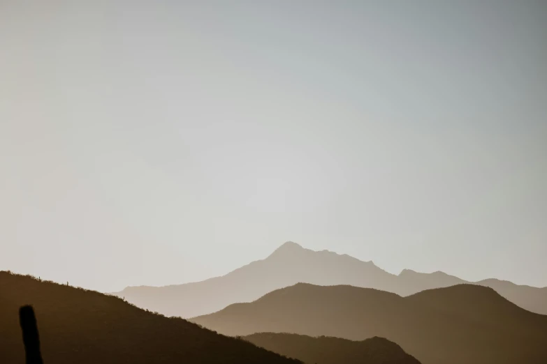 the silhouette of hills and mountains against a pale sky