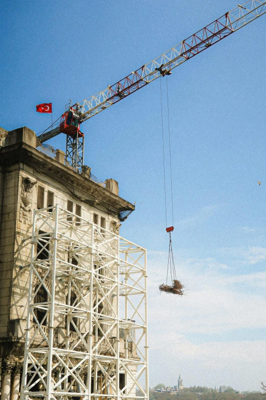 two cranes, one being lifted over by a crane