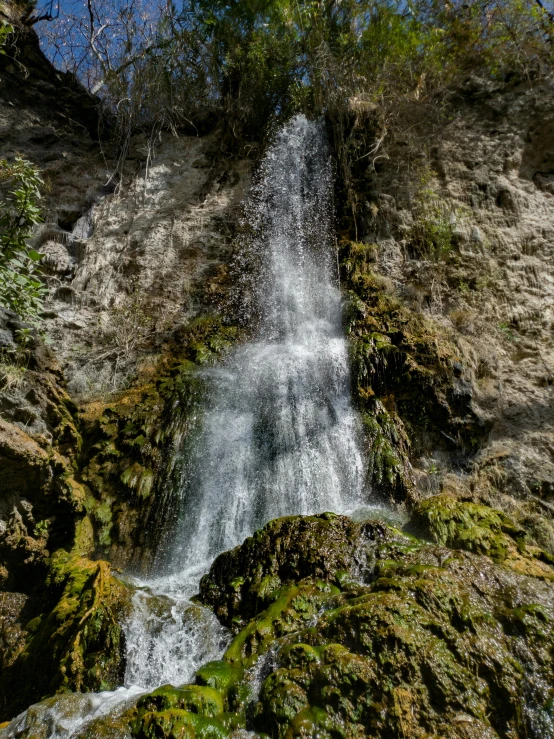 there is a waterfall near the rocks and trees