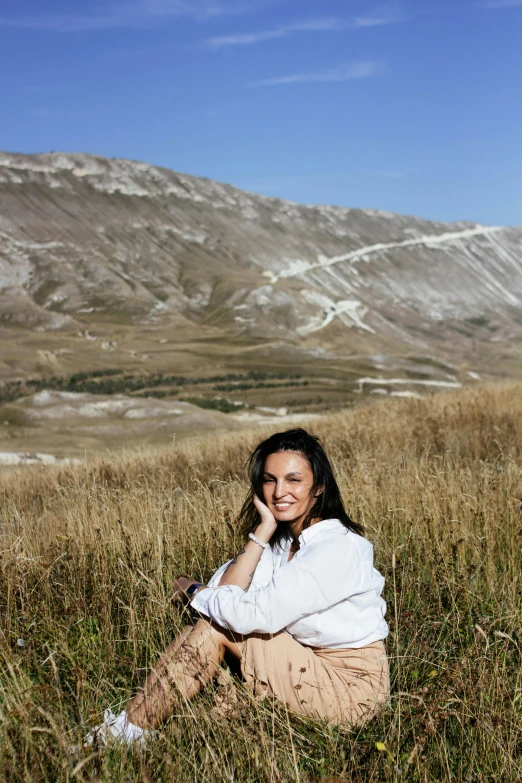 a  sitting on the ground in a field of tall grass