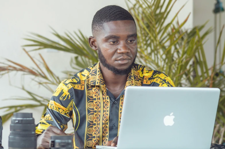 an african american man looking confused while working on his laptop